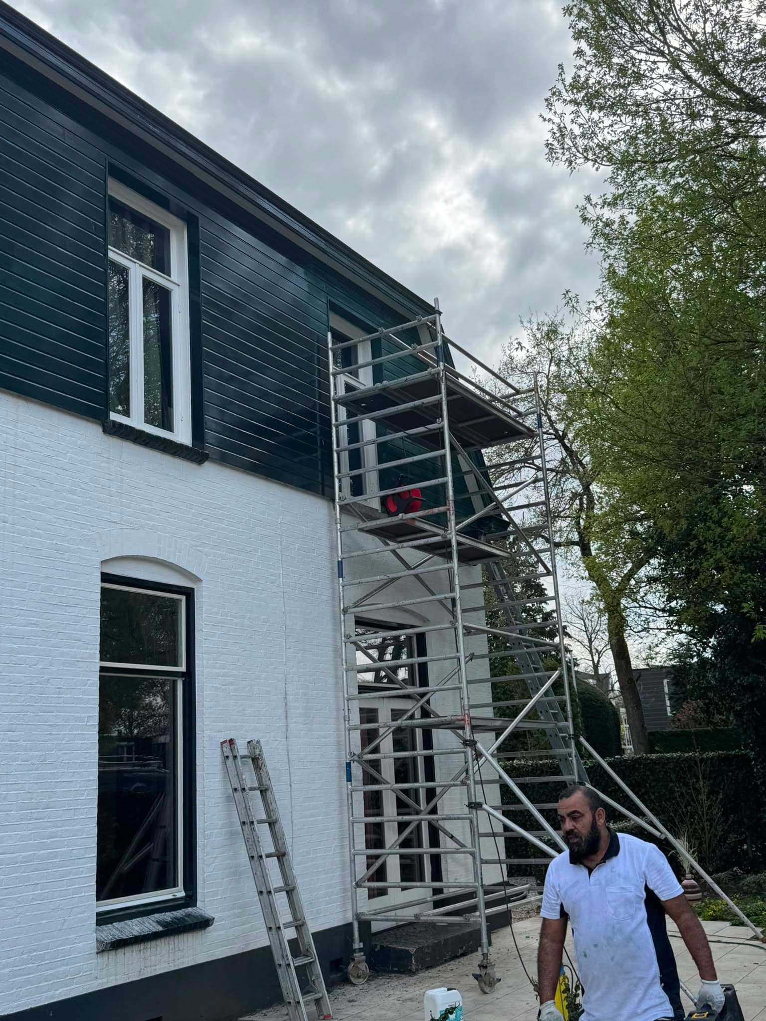Volledig geschilderde gevel van een woning met steiger